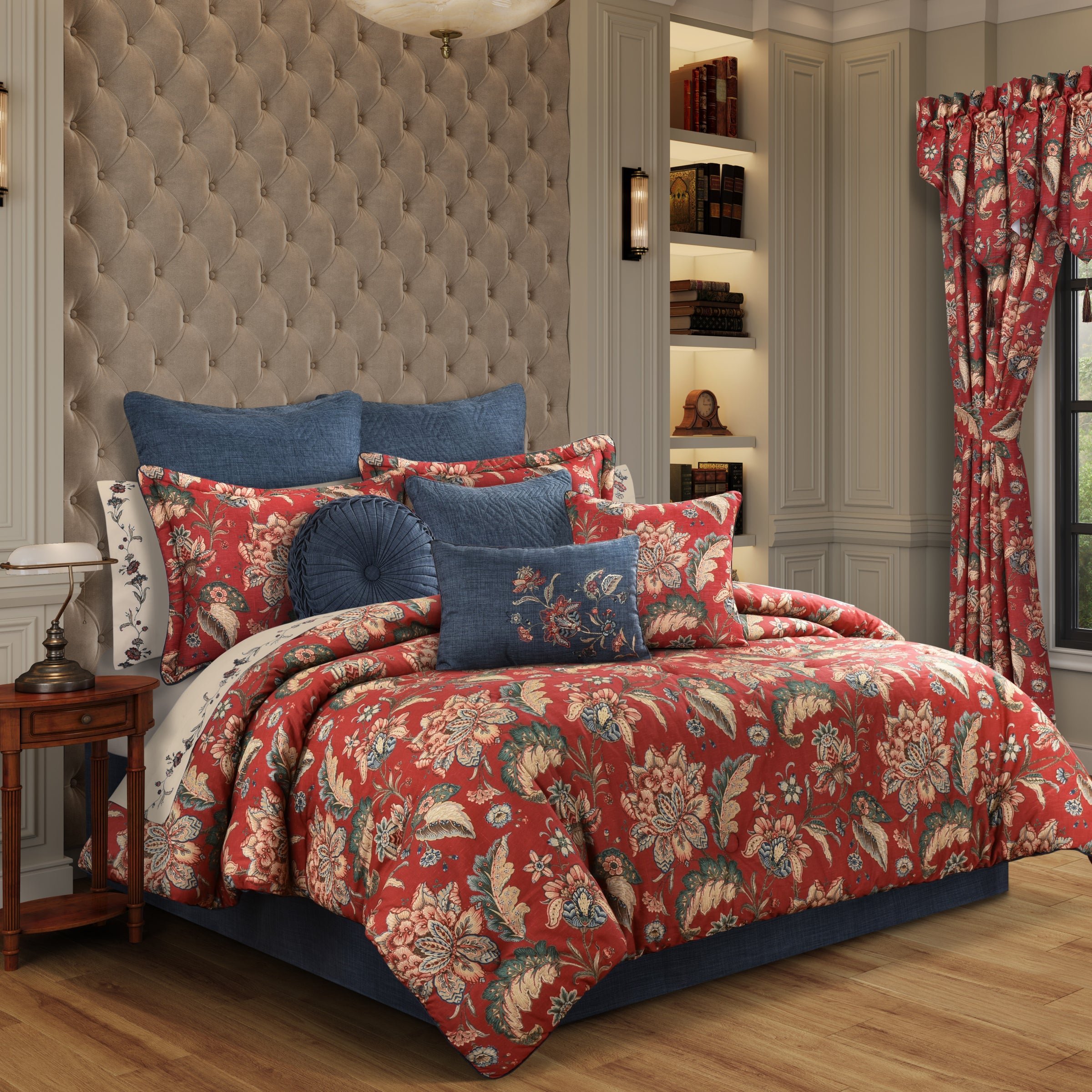 Red floral bedding set in a bedroom with a patterned headboard and curtains.