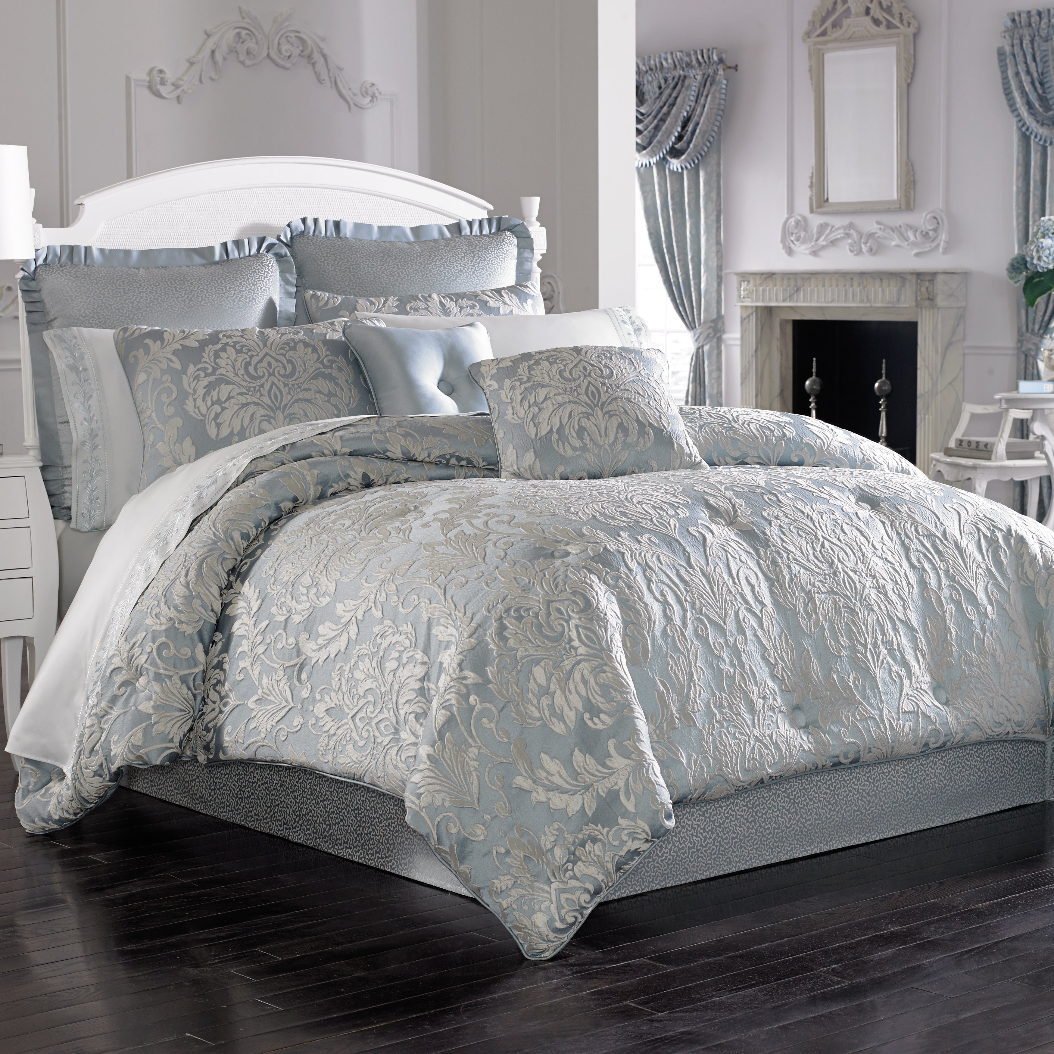 Decorative bedspread set on a bed in a bedroom with a fireplace and mirror.