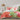 Bed with colorful floral bedding against a gray tiled wall.
